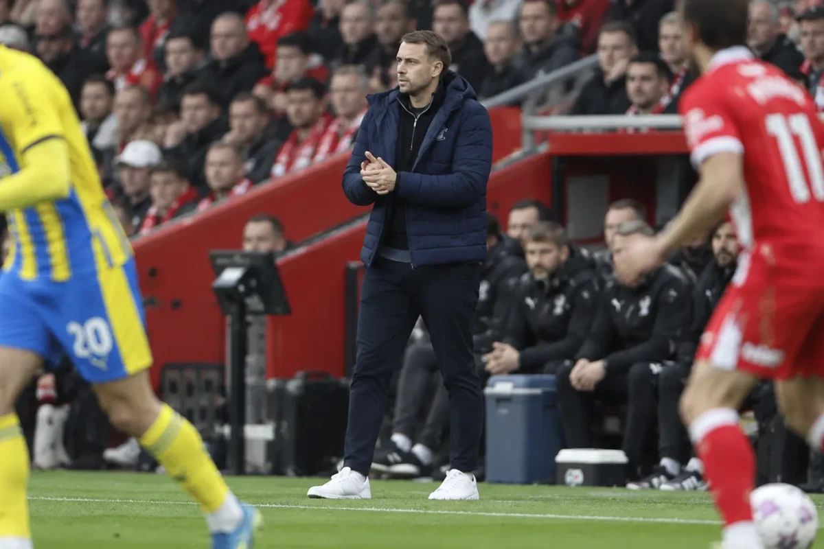 Tonda Eckert staat in een donkere jas langs de zijlijn tijdens een wedstrijd van Southampton.
