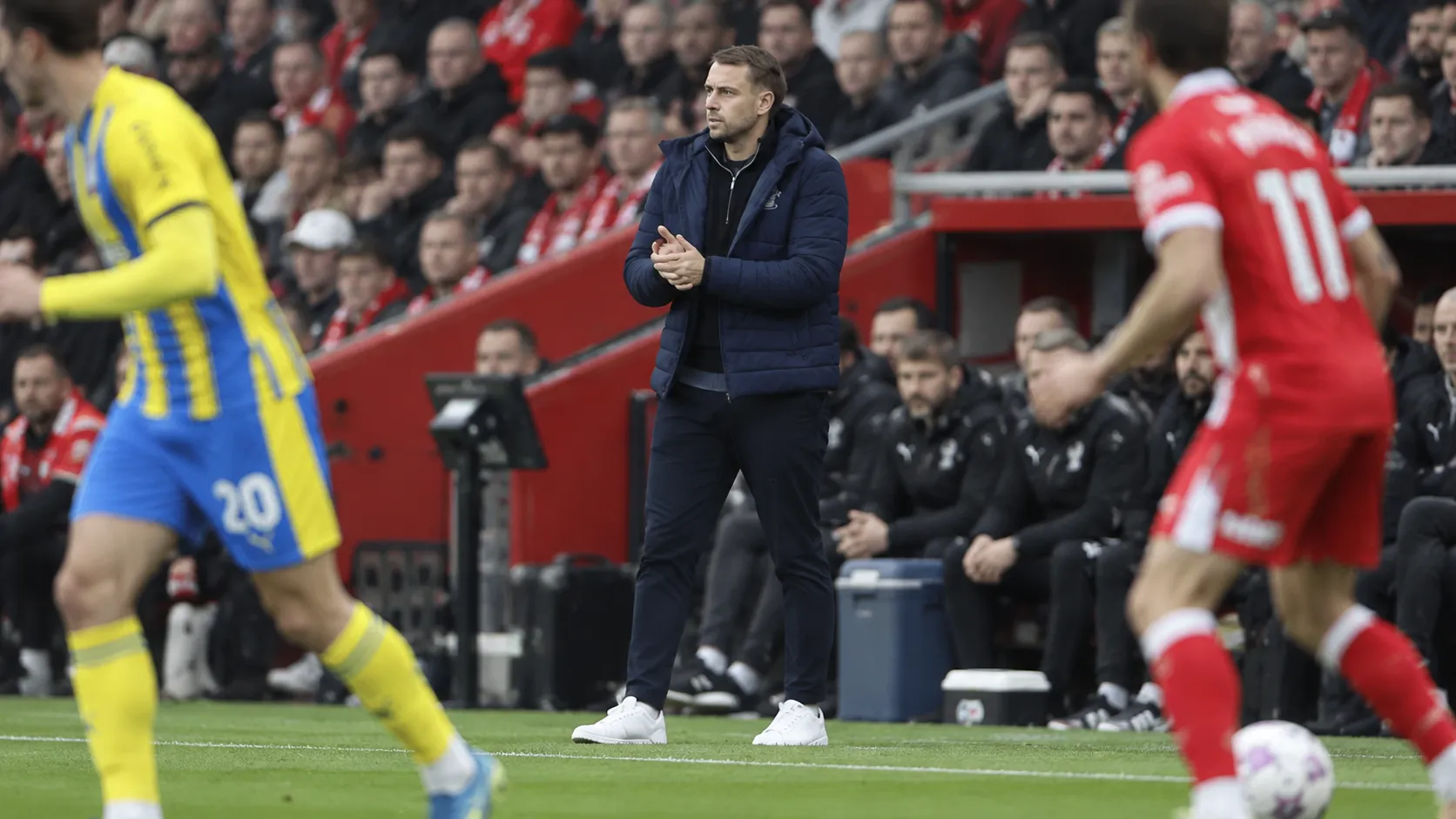 Tonda Eckert staat in een donkere jas langs de zijlijn tijdens een wedstrijd van Southampton.