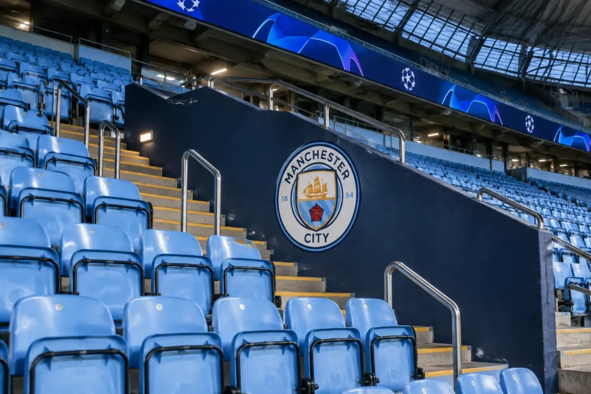 Lege tribune in het Etihad Stadium met een Manchester City-embleem aan de wand.