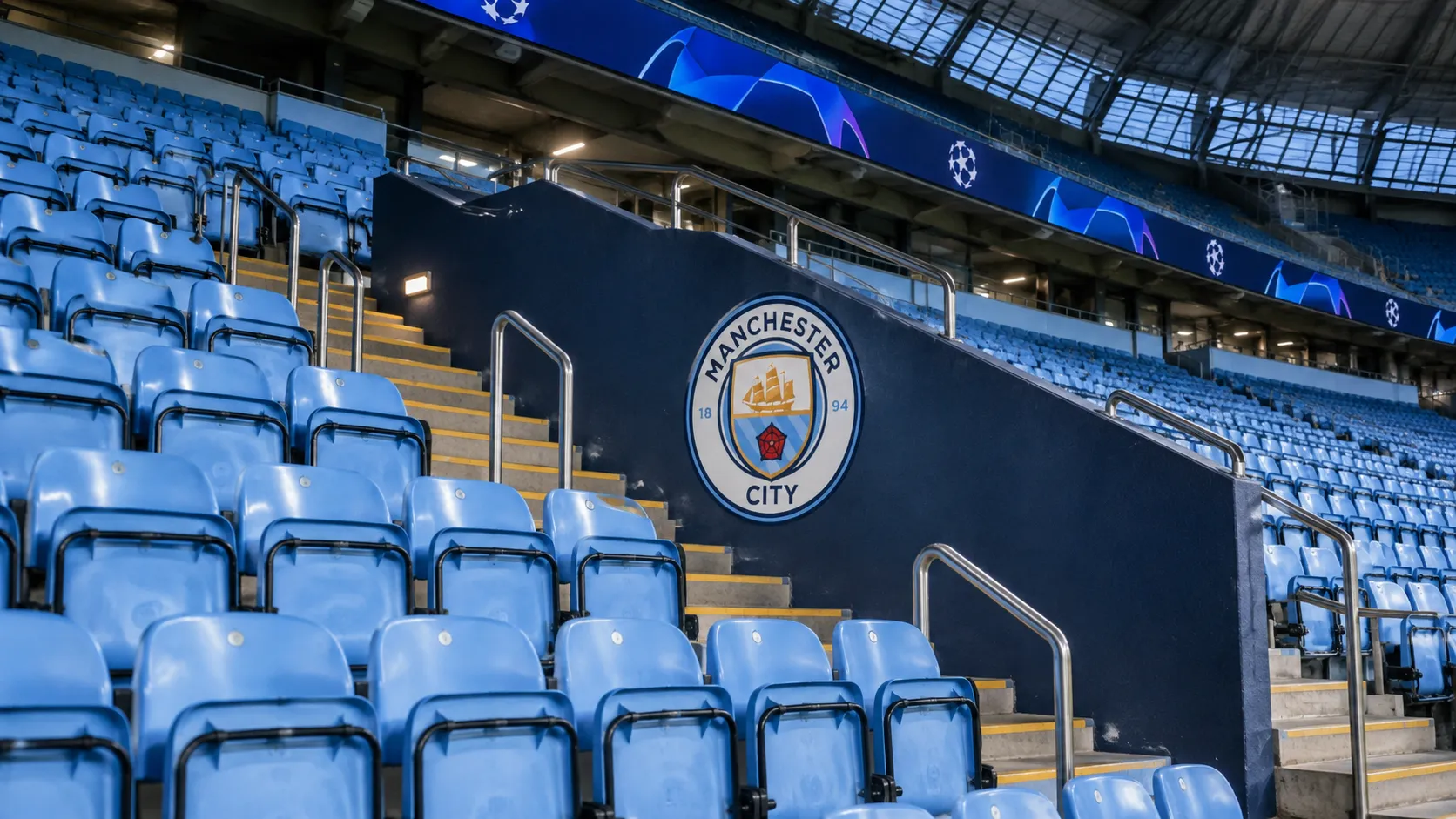 Lege tribune in het Etihad Stadium met een Manchester City-embleem aan de wand.
