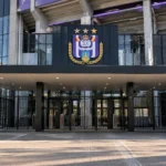 De hoofdingang van het Lotto Park met een RSC Anderlecht-embleem op het gevelbord.