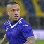 Radja Nainggolan in een paars voetbalshirt op een regenachtig veld.
