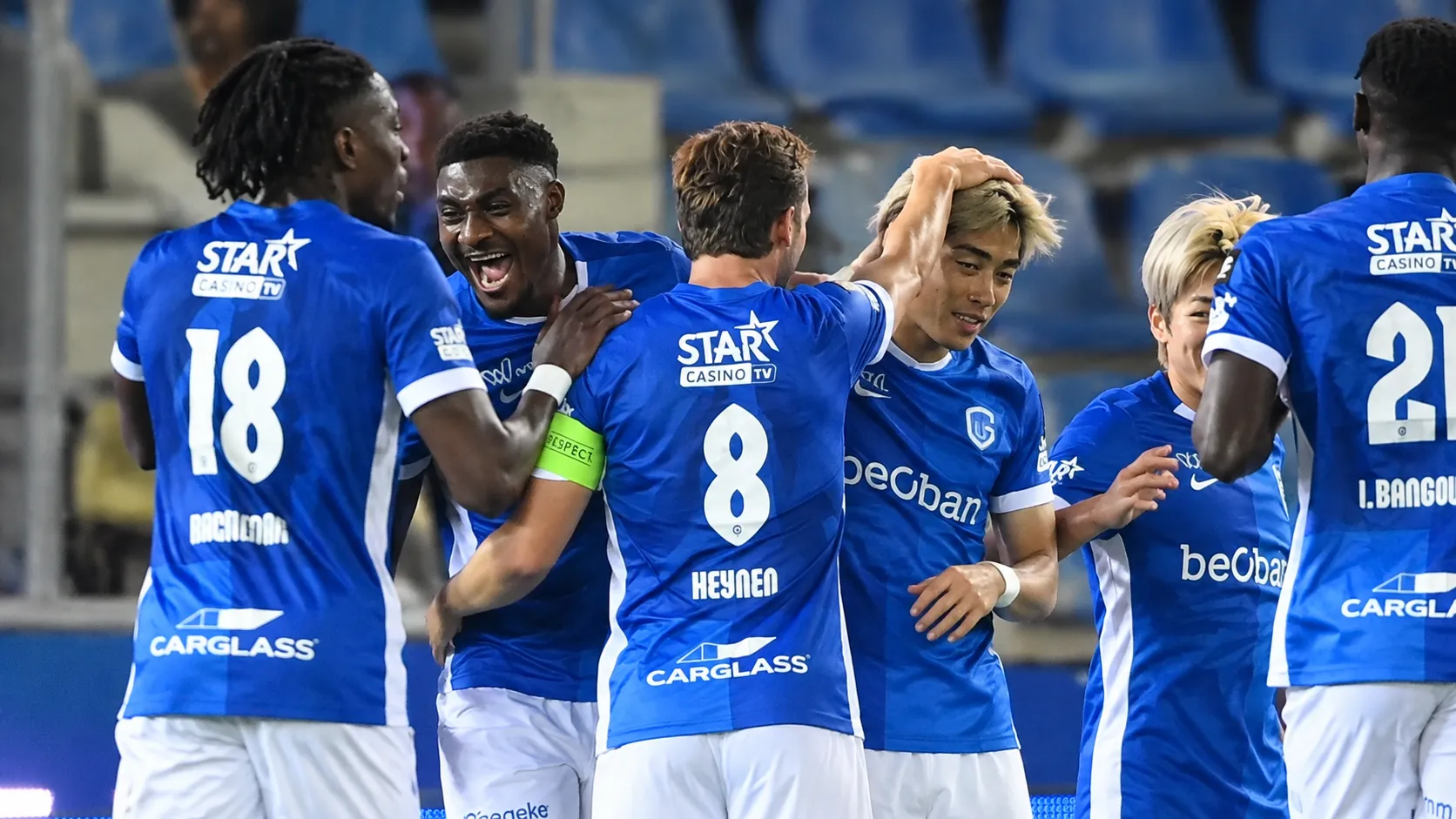 Een groep KRC Genk-spelers viert samen op het veld in blauwe shirts.