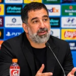 Arda Turan tijdens een voetbalpersconferentie achter een microfoon.