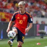 Dani Olmo warmt op in het Spaanse wedstrijdshirt aan de rand van een voetbalveld.