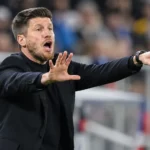 Sébastien Pocognoli in donkere coachkleding terwijl hij langs de zijlijn aanwijzingen geeft.