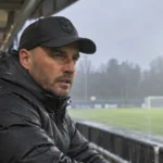 Stijn Stijnen kijkt vanuit een overdekte tribune uit over een voetbalveld.