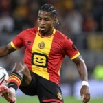 Simion Michez van KV Mechelen controleert de bal in een verlichte voetbalomgeving.