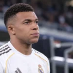 Kylian Mbappé in een wit shirt van Real Madrid in een stadionomgeving.