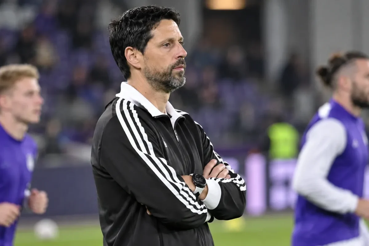 Vitor Bruno in een zwart-witte coachjas aan de zijlijn voor een wedstrijd.