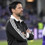 Vitor Bruno in een zwart-witte coachjas aan de zijlijn voor een wedstrijd.