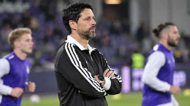 Vitor Bruno in een zwart-witte coachjas aan de zijlijn voor een wedstrijd.