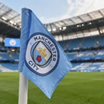 Een lichtblauwe Manchester City-hoekvlag naast het voetbalveld in een stadion.
