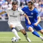 Twee voetballers van Club Brugge en KAA Gent vechten om balbezit tijdens een wedstrijd.