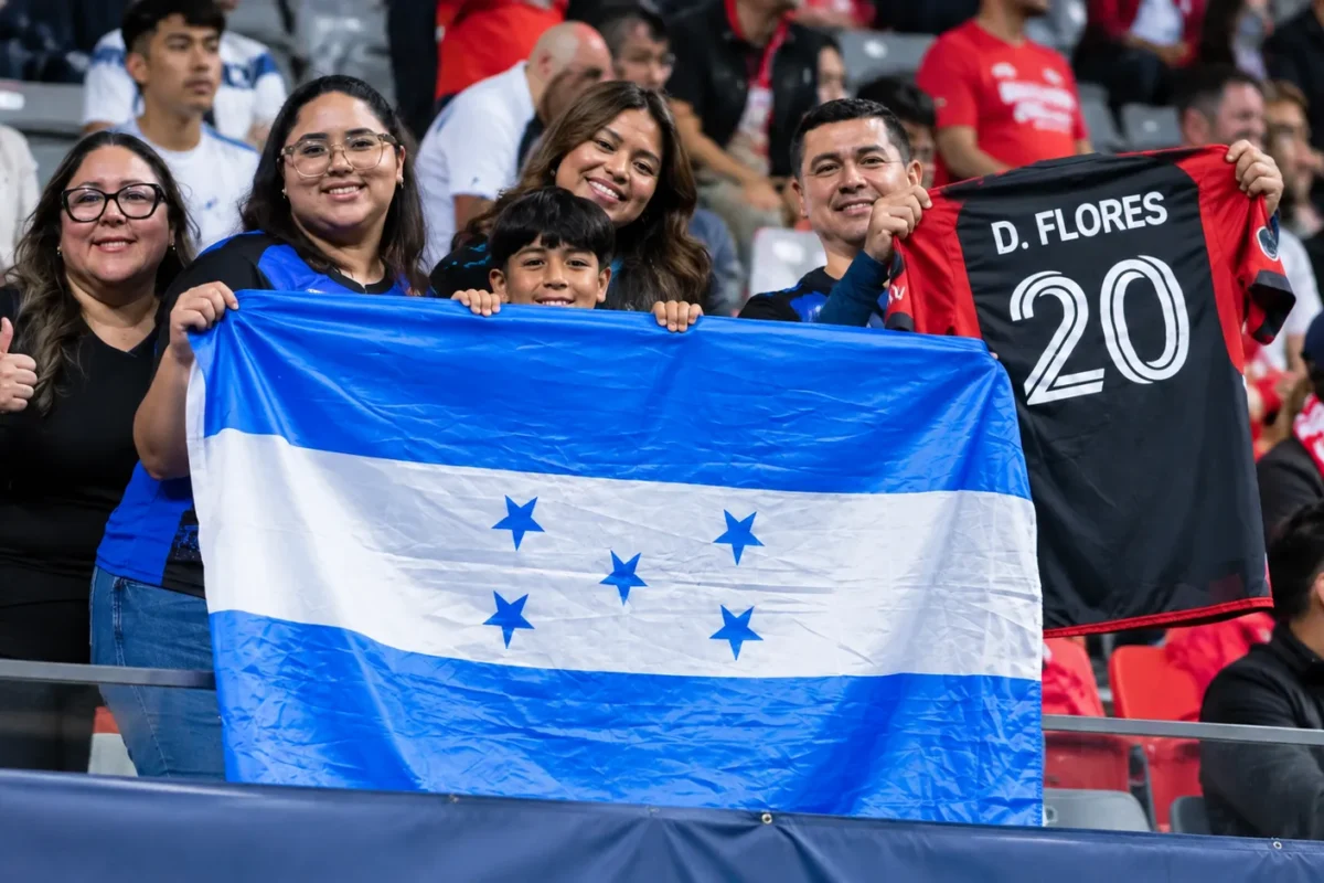 Een groep supporters houdt een blauw-witte Hondurese vlag vast op de tribune.