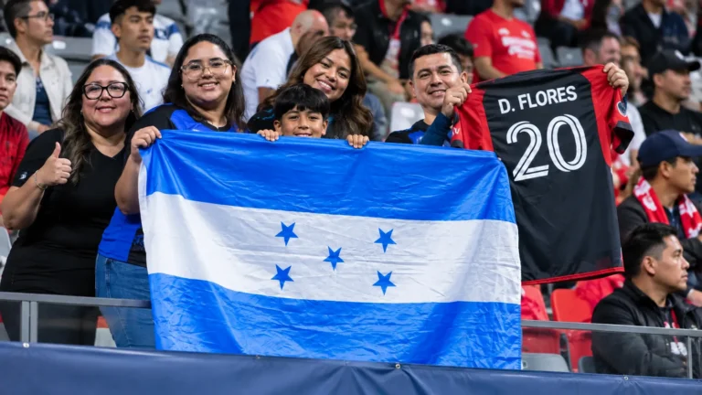 Een groep supporters houdt een blauw-witte Hondurese vlag vast op de tribune.