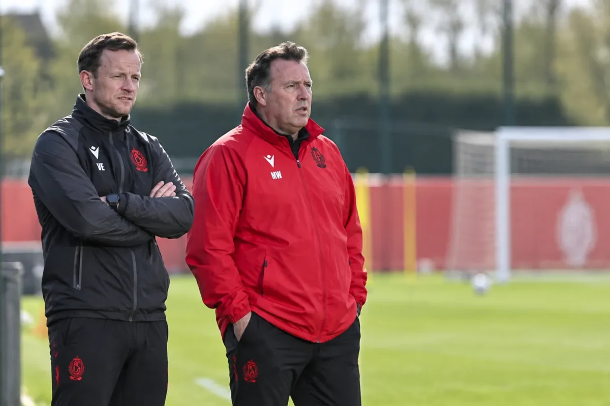 Twee stafleden van Standard volgen een training langs het veld.