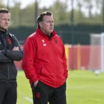 Twee stafleden van Standard volgen een training langs het veld.
