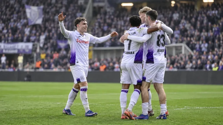 Een groep Anderlecht-spelers viert samen op het veld in wit-paars tenue.