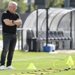 Lars Friis staat langs een trainingsveld en observeert de oefenmaterialen.