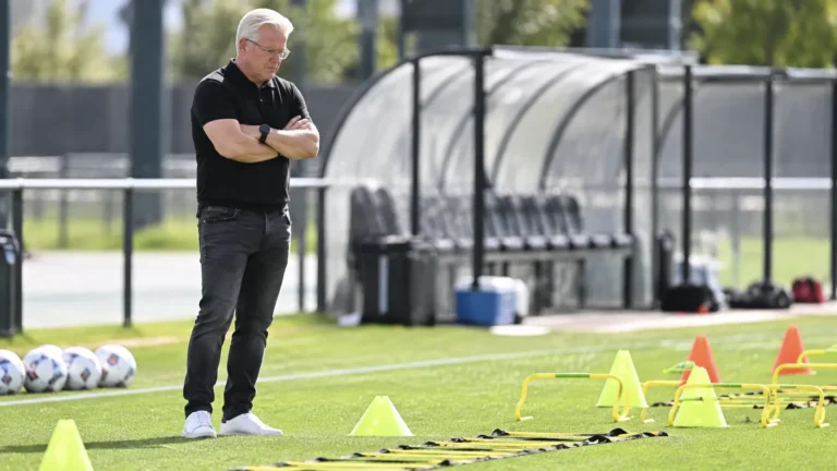 Lars Friis staat langs een trainingsveld en observeert de oefenmaterialen.