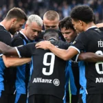 Een groep spelers van Club Brugge vormt een hechte huddle op het veld.