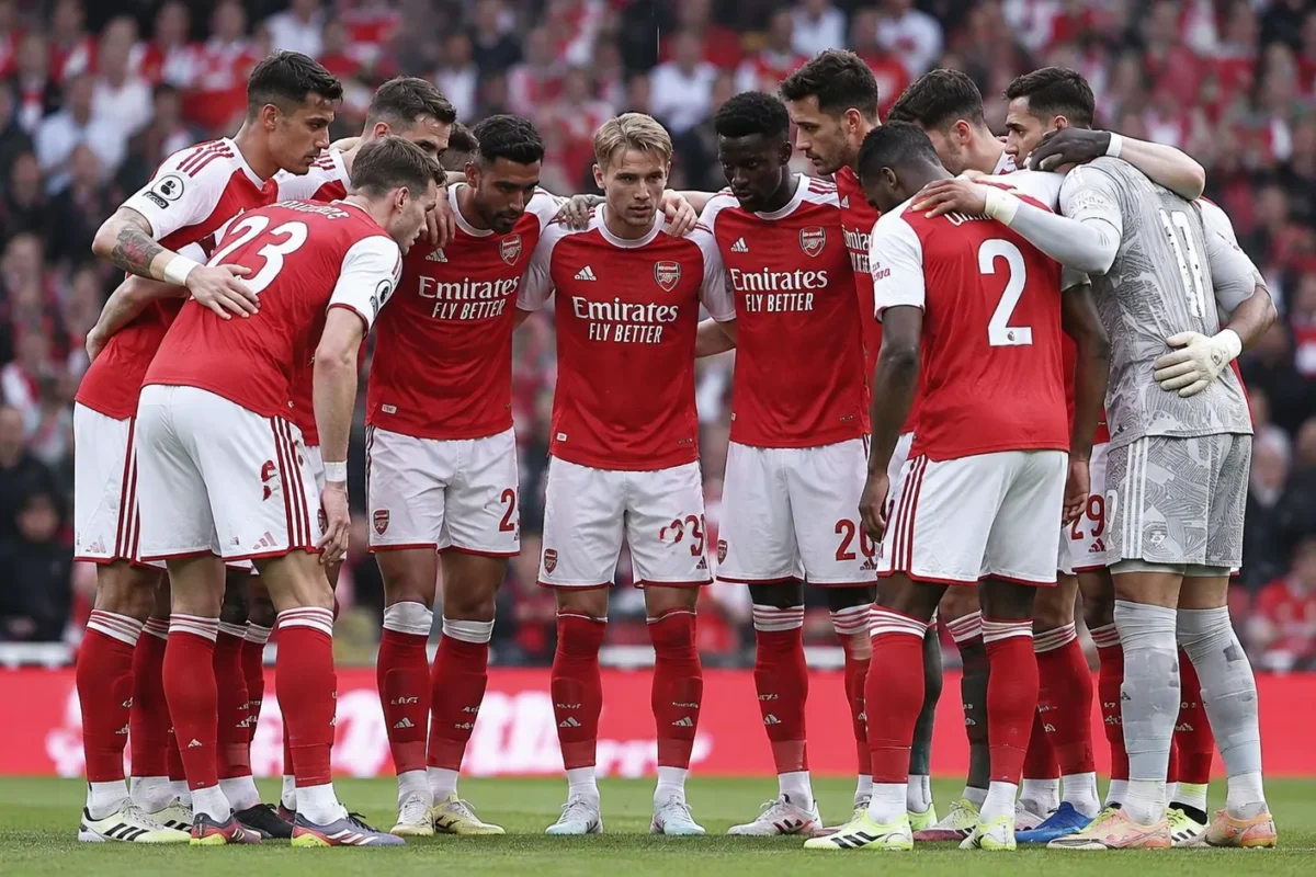 Een groep Arsenal-spelers in rood-witte tenues verzamelt zich op het veld voor een wedstrijd.