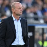 Jess Thorup staat geconcentreerd in de technische zone van een voetbalstadion.