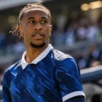 Michael Olise in een donkerblauw internationaal shirt langs de zijlijn van een stadion.
