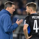 Een speler van Club Brugge en een staflid overleggen langs de zijlijn.