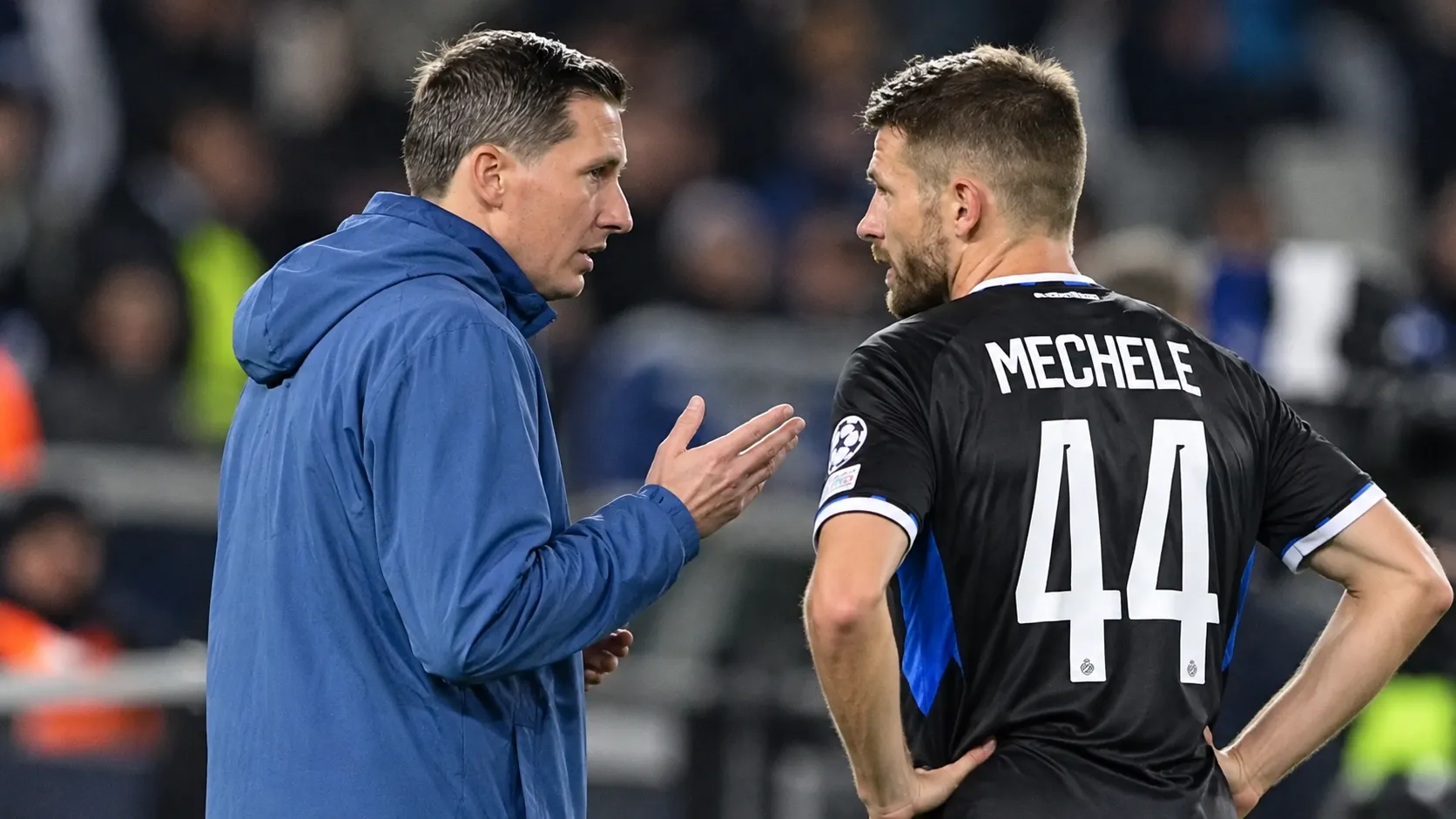 Een speler van Club Brugge en een staflid overleggen langs de zijlijn.