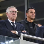 Vier bondscoaches in de overdekte tribunezone van een stadion.