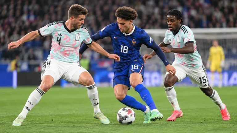 Drie voetballers in een verdedigend duel tijdens een interland.