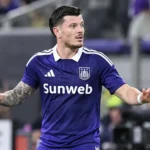 Giulian Biancone van Anderlecht staat met gespreide armen op het veld.