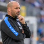 Stijn Stijnen in Patro Eisden-kleding aan de zijlijn van een stadion.
