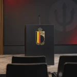 Lege persruimte van de Rode Duivels met een lessenaar voorzien van het nationale embleem.