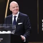 Een FIFA-official in donker pak voor het decor van een WK-loting.