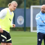 Een Manchester City-trainer en speler tijdens een trainingsmoment op het oefenterrein.
