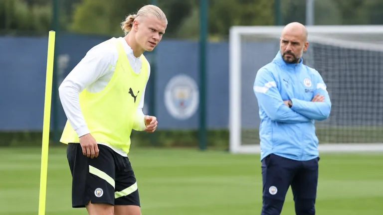 Een Manchester City-trainer en speler tijdens een trainingsmoment op het oefenterrein.