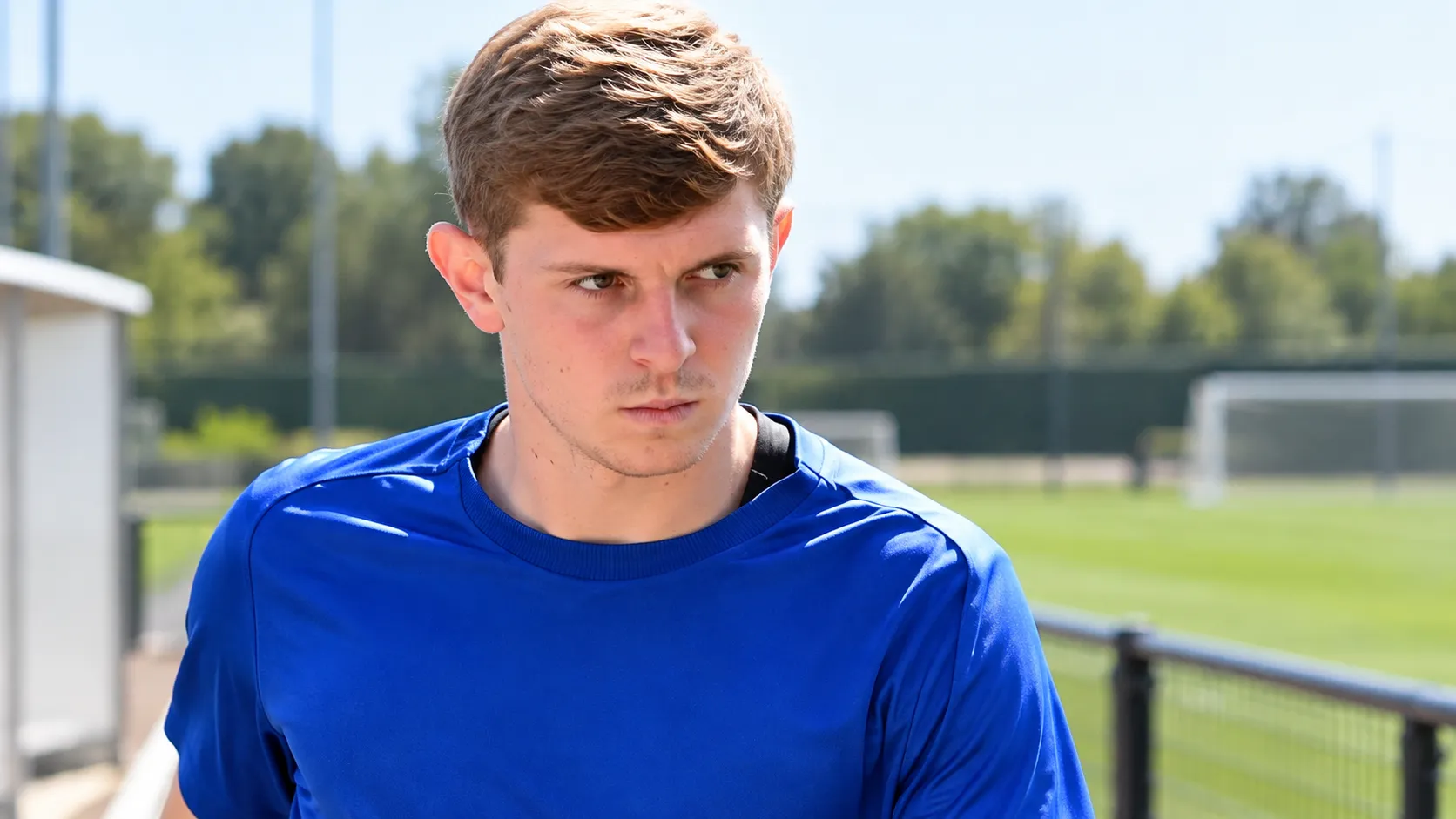 Max Dean in blauw sportshirt tijdens een gefocust moment in een buitenomgeving.