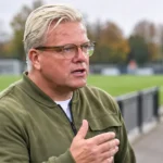 Lars Friis spreekt naast een voetbalveld in een rustige clubomgeving.