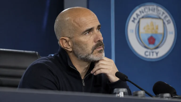 Enzo Maresca tijdens een persmoment met een Manchester City-embleem op de achterwand.