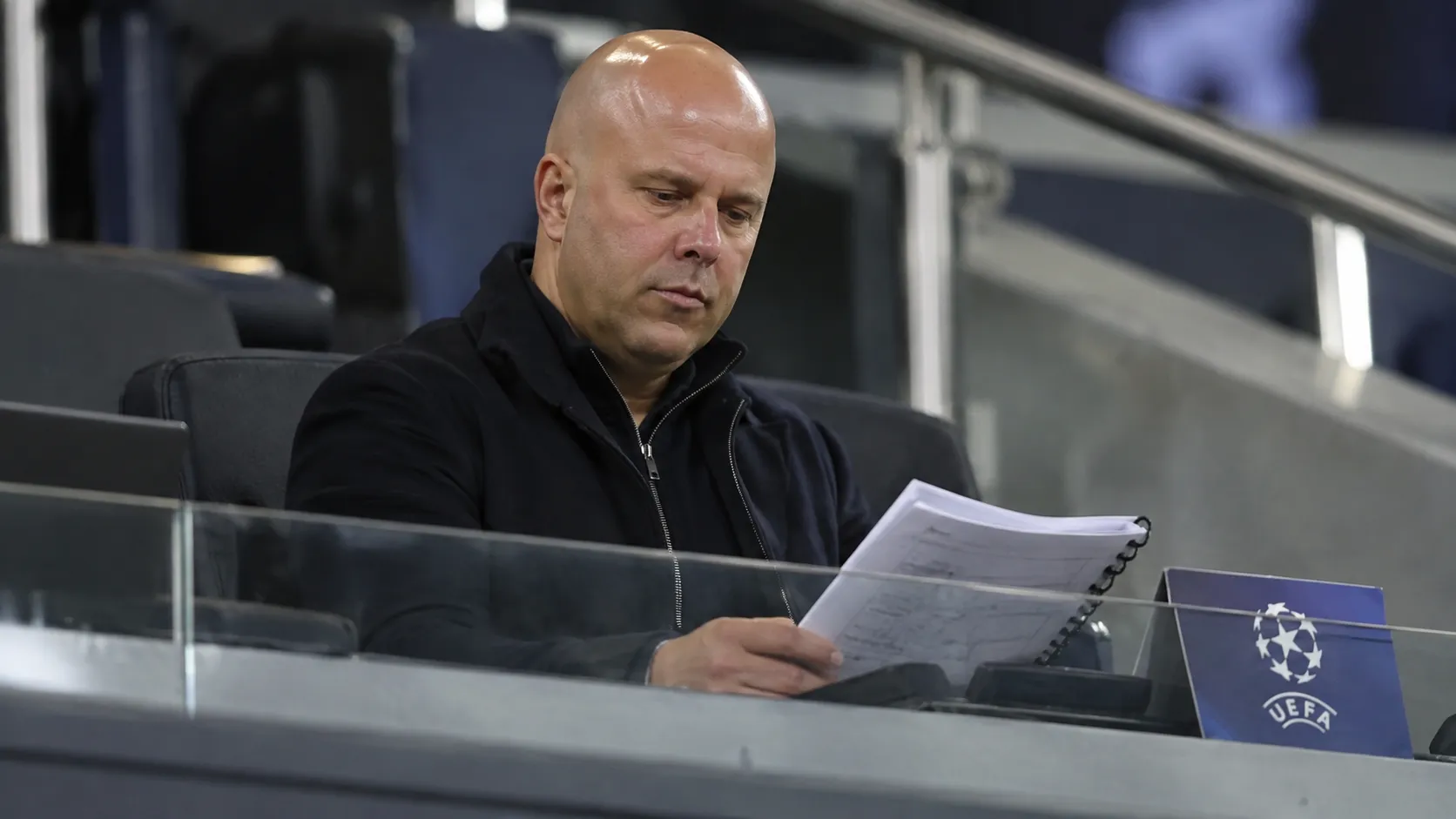 Arne Slot in een UEFA-observatieruimte op de tribune met wedstrijdnotities.