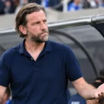 Rik De Mil in een donkere polo naast de dug-out van KAA Gent.