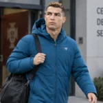Cristiano Ronaldo in een blauwe gewatteerde jas bij het verlaten van een trainingscomplex.