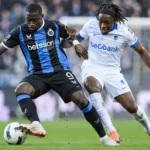Twee voetballers van Club Brugge en KRC Genk vechten om balbezit in een duel.