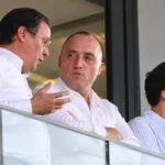 Drie niet-spelende clubvertegenwoordigers in een stadionloge tijdens een gesprek.