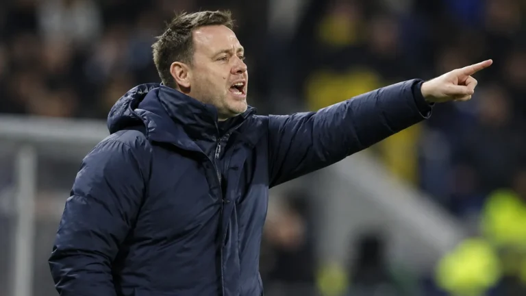 Michael Beale geeft aanwijzingen vanaf de zijlijn in een donker gewatteerd coachjack.