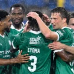 Lommel-spelers vieren samen tijdens een regenachtige voetbalwedstrijd.