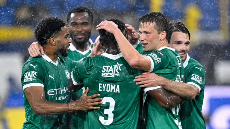 Lommel-spelers vieren samen tijdens een regenachtige voetbalwedstrijd.